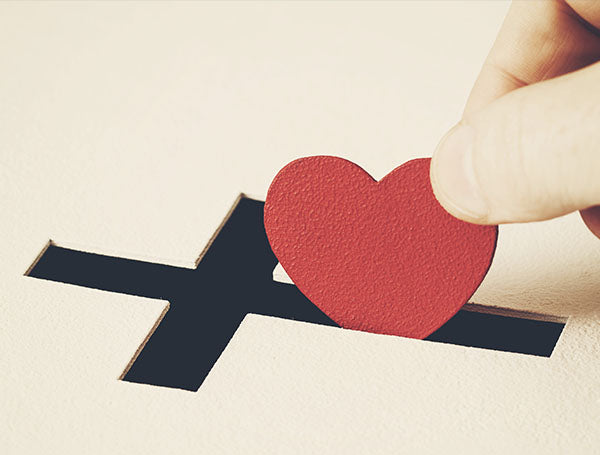 Heart being placed in a cross-shaped slot in a box.